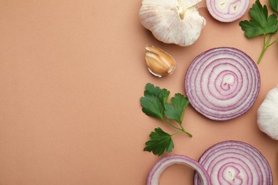 Photo of Fresh red onions, garlic and parsley on beige background, flat lay. Space for text