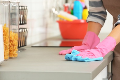 Photo of Woman cleaning kitchen counter with rag, closeup