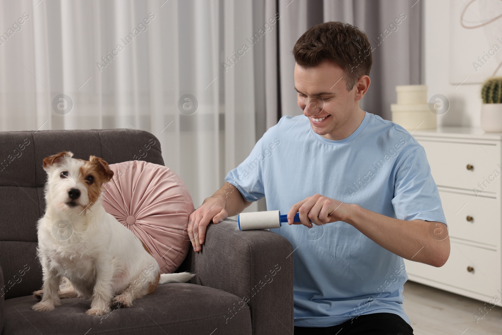 Photo of Smiling man removing pet's hair from armchair at home