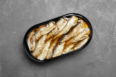 Canned sprats on grey textured table, top view