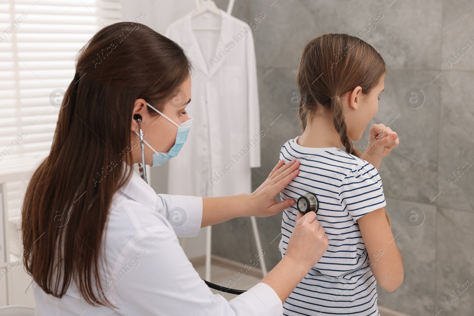 Photo of Doctor examining coughing girl in hospital. Cold symptoms