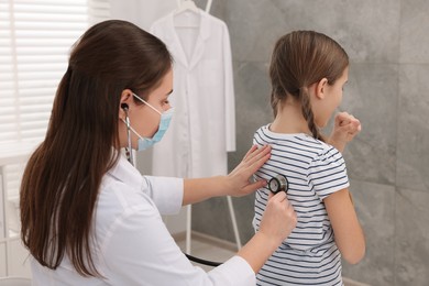 Doctor examining coughing girl in hospital. Cold symptoms