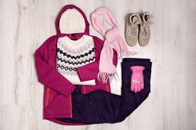 Flat lay composition with female clothes for winter vacation on wooden background
