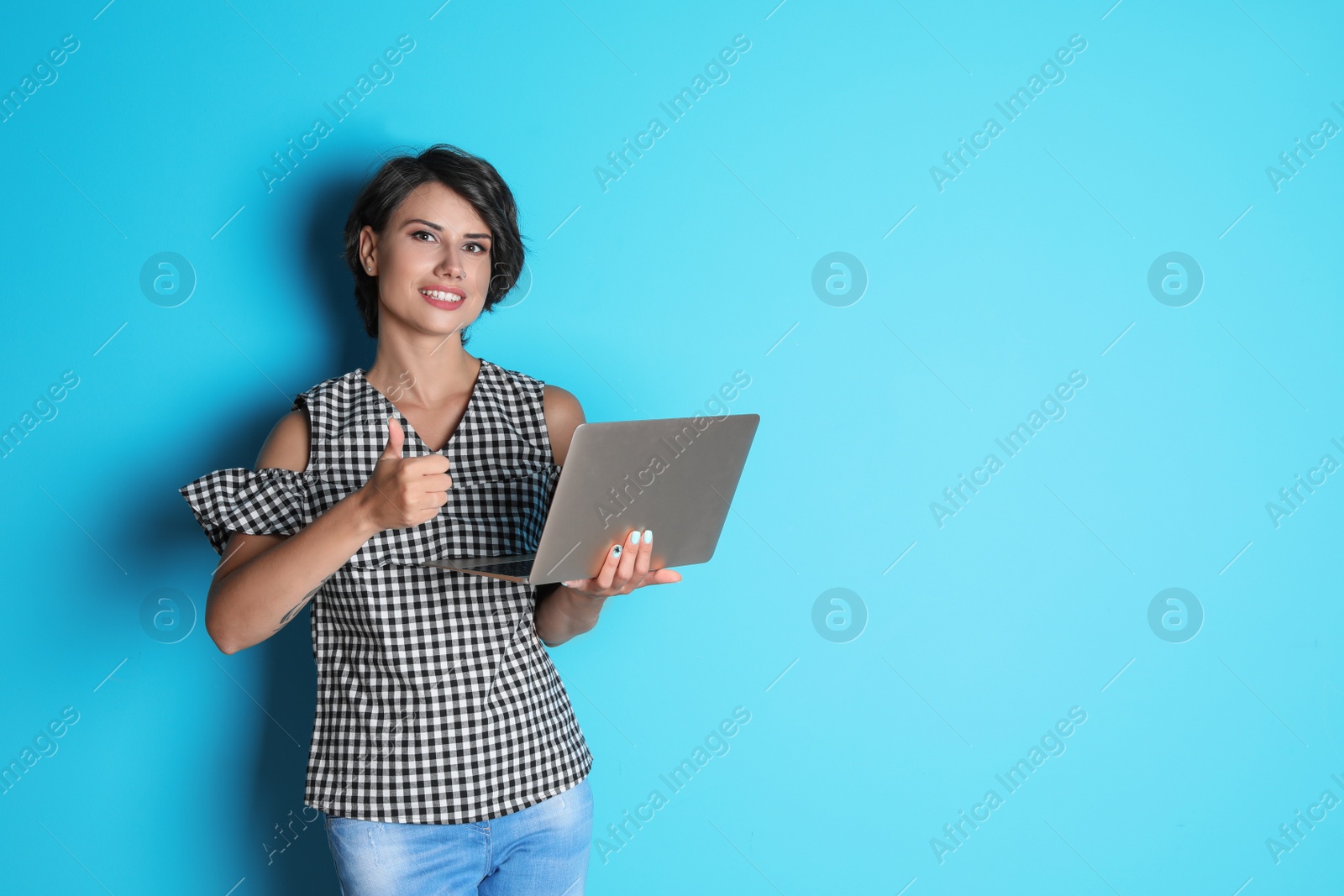 Photo of Young woman with modern laptop on color background