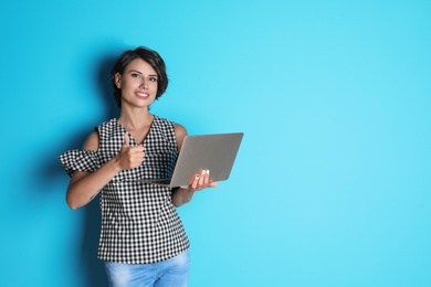 Photo of Young woman with modern laptop on color background