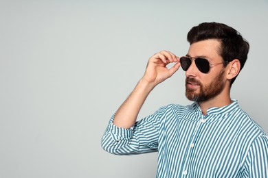 Portrait of bearded man with sunglasses on grey background. Space for text