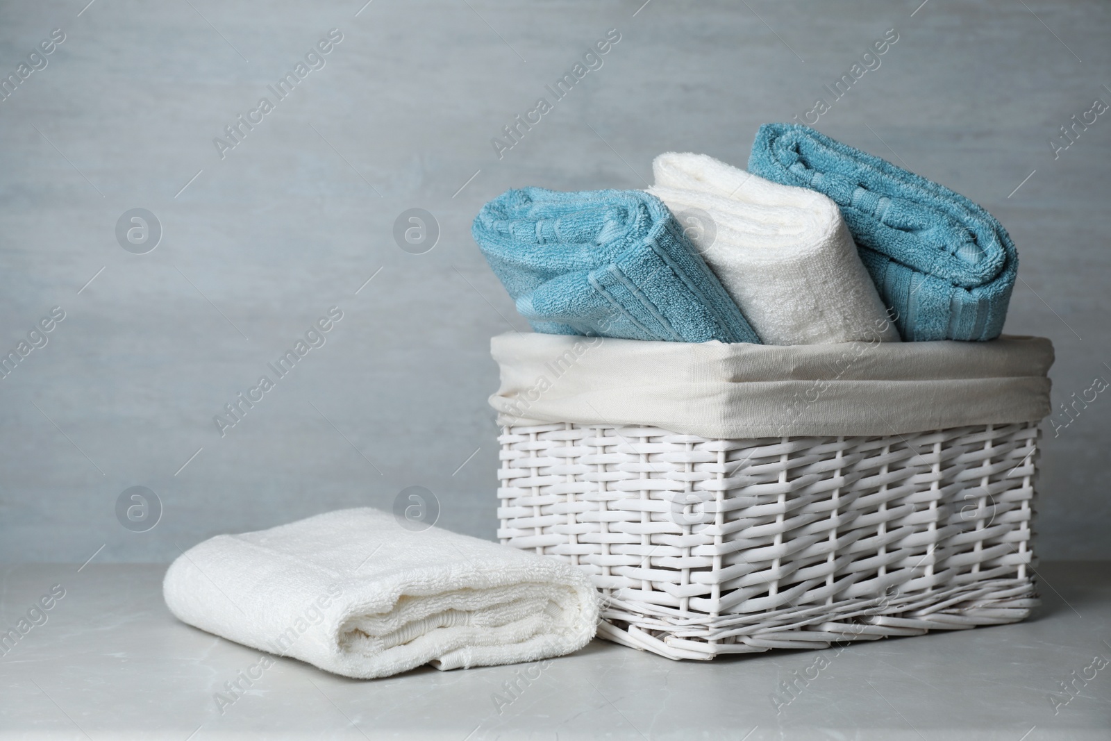 Photo of Basket with soft bath towels on table. Space for text