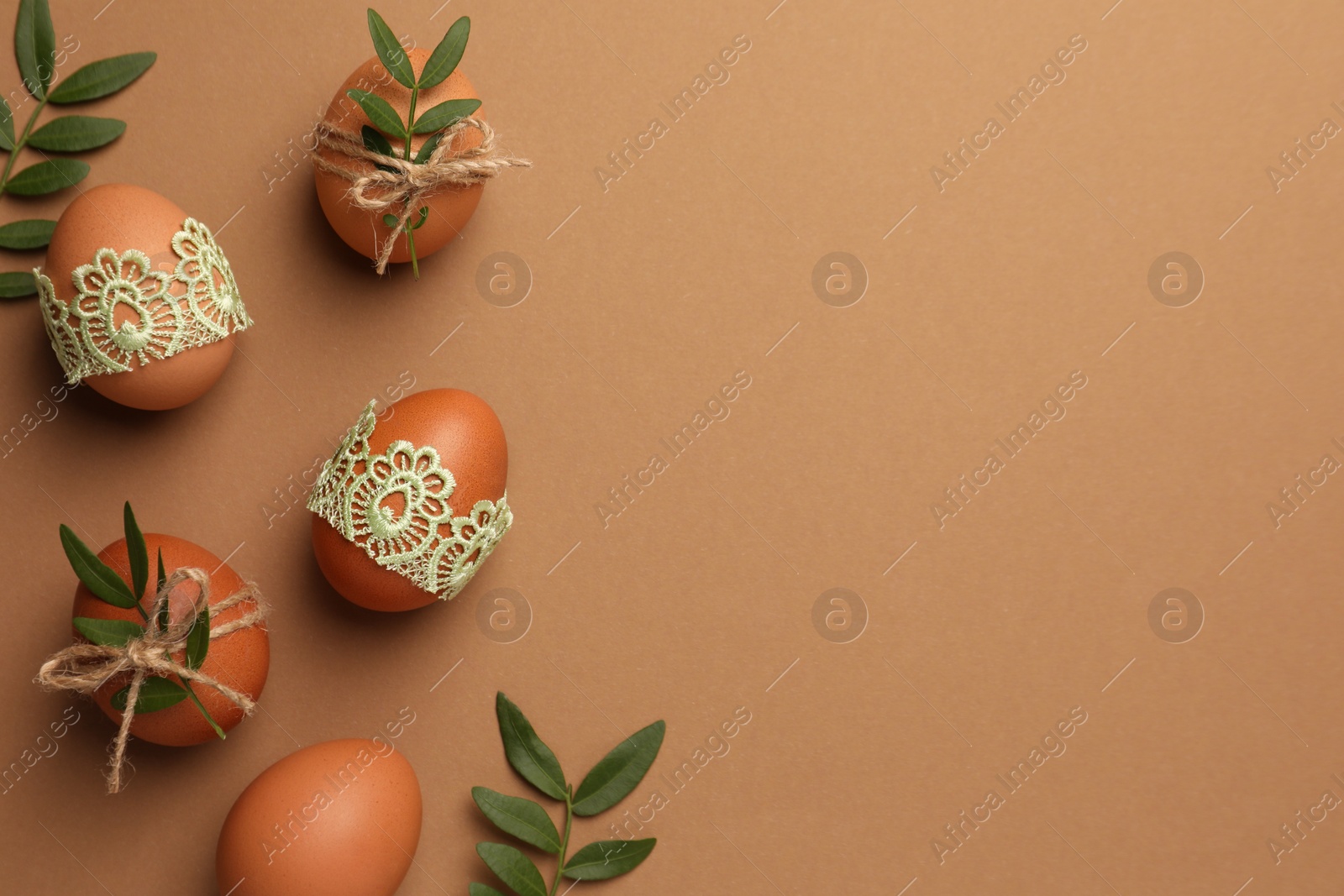 Photo of Festively decorated chicken eggs on brown background, flat lay and space for text. Happy Easter