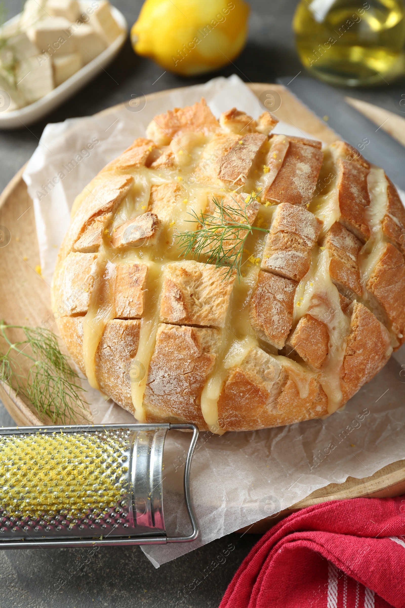 Photo of Freshly baked bread with tofu cheese, lemon zest and grater on grey table