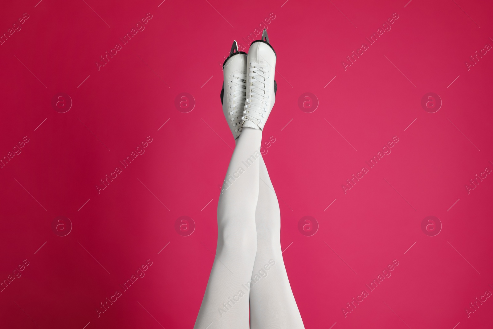 Photo of Woman in elegant white ice skates on pink background, closeup of legs