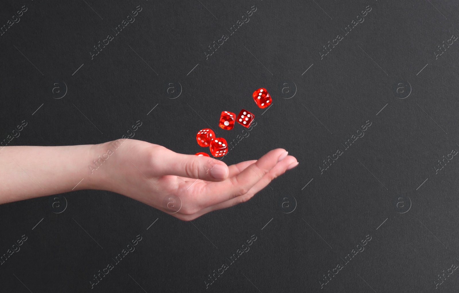 Photo of Woman throwing game dices on black background, closeup