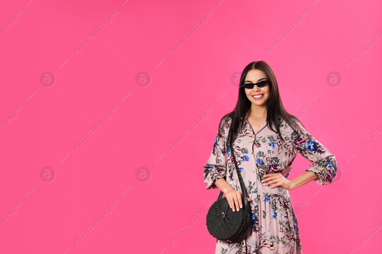 Photo of Young woman wearing floral print dress and sunglasses on pink background. Space for text