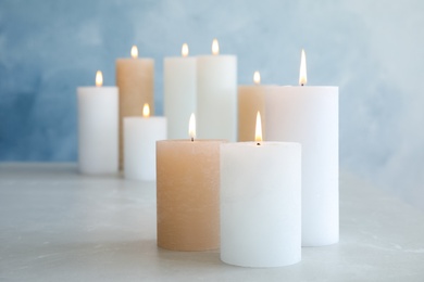 Photo of Burning candles on table against color background. Space for text