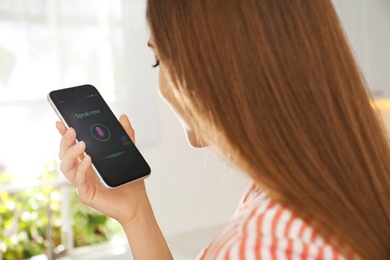 Photo of Woman using voice search on smartphone indoors, closeup