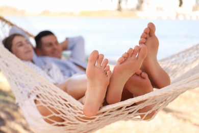 Photo of Couple relaxing in hammock on beach, focus on legs. Summer vacation
