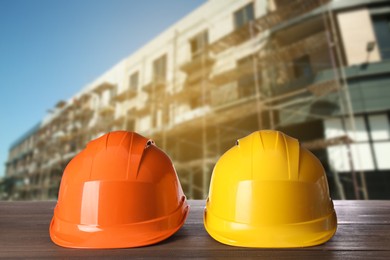 Image of Safety equipment. Hard hats on wooden surface near unfinished building outdoors, space for text