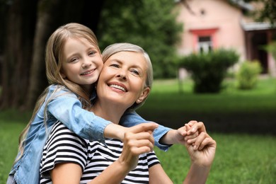 Photo of Happy grandmother with her granddaughter spending time together in park, space for text