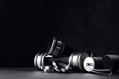 Photo of Gym equipment and accessories on floor against dark background. Space for text