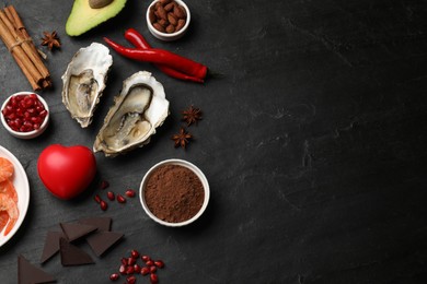 Photo of Natural aphrodisiac. Different food products and heart model on black table, flat lay. Space for text