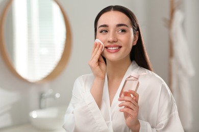 Photo of Beautiful woman removing makeup with cotton pad indoors
