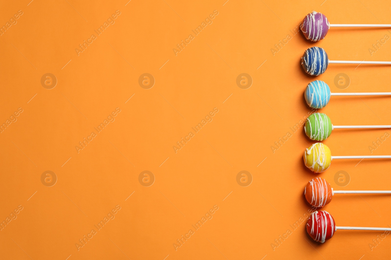 Photo of Bright delicious cake pops on color background, flat lay. Space for text