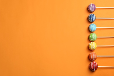 Photo of Bright delicious cake pops on color background, flat lay. Space for text