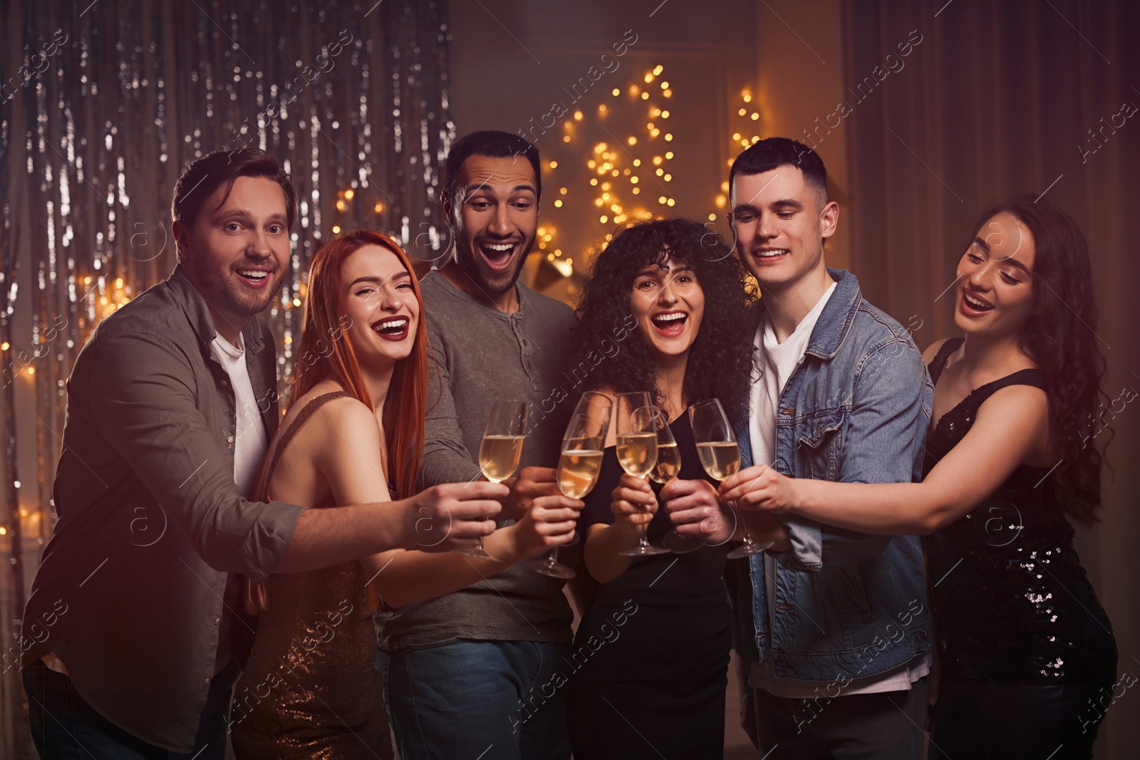 Photo of Happy friends with glasses of sparkling wine celebrating birthday indoors