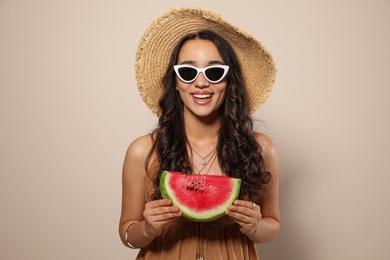 Beautiful young woman with watermelon on beige background