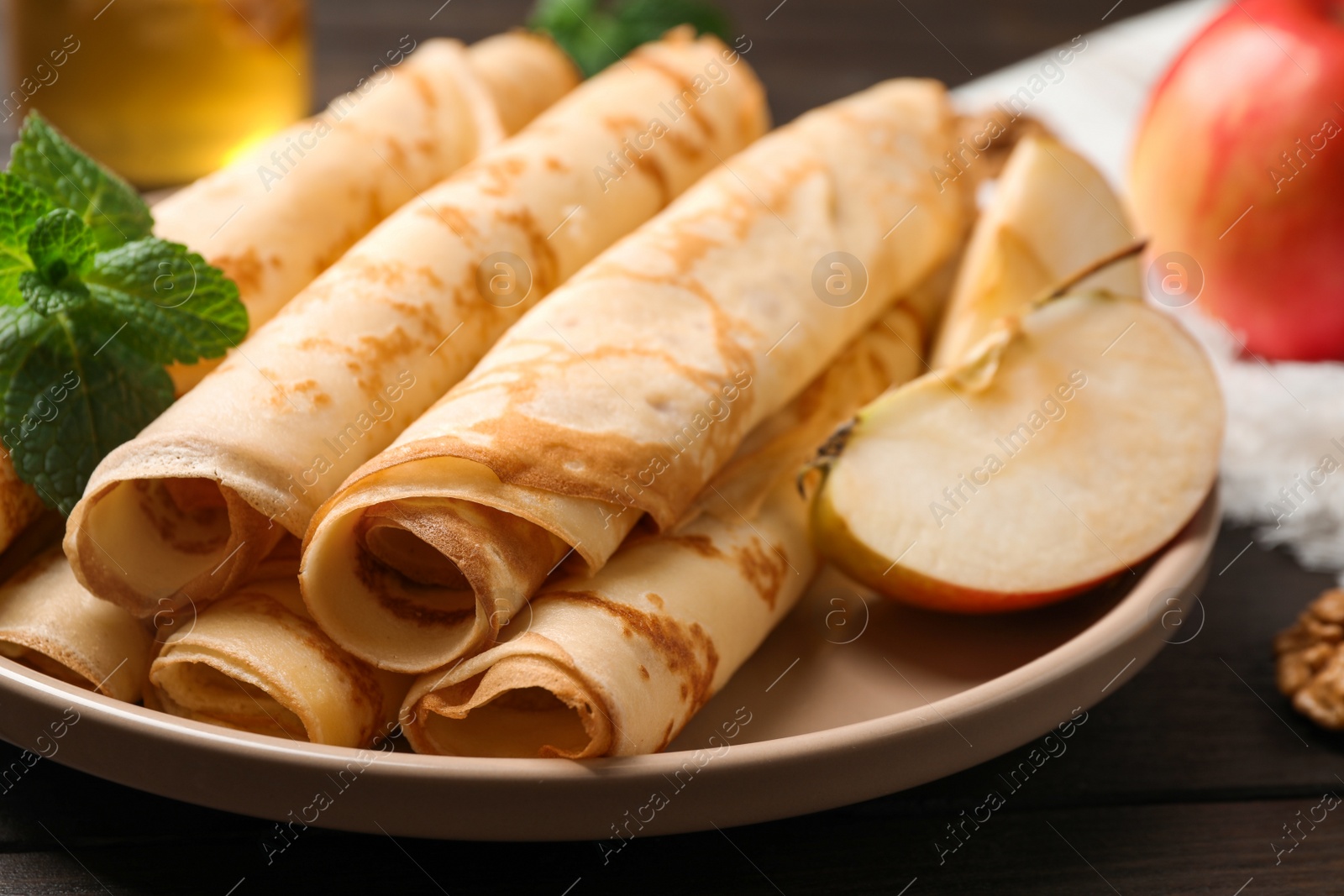 Photo of Delicious rolled  thin pancakes on wooden table, closeup