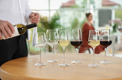 Waiter pouring wine into glass in restaurant, closeup