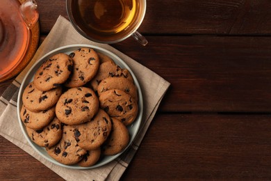 Photo of Delicious chocolate chip cookies and tea on wooden table, flat lay. Space for text