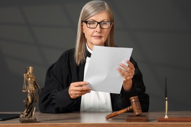 Photo of Judge in court dress working with document indoors