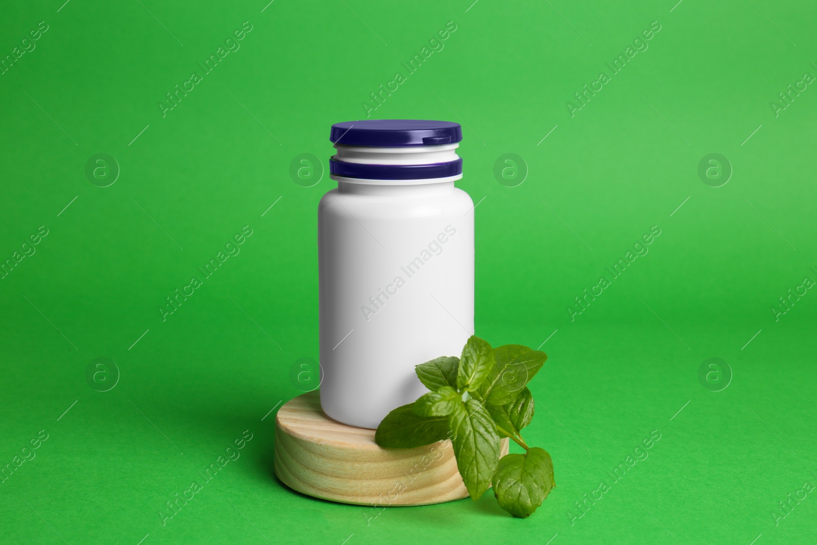 Photo of Plastic medicine bottle and leaves on green background. Medicament