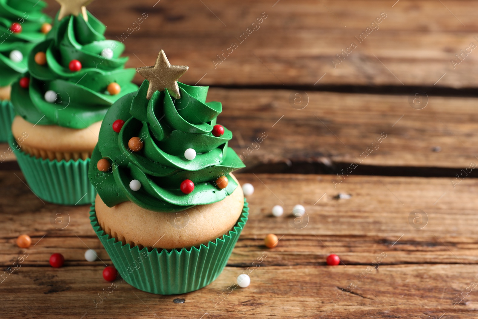 Photo of Christmas tree shaped cupcakes on wooden table. Space for text