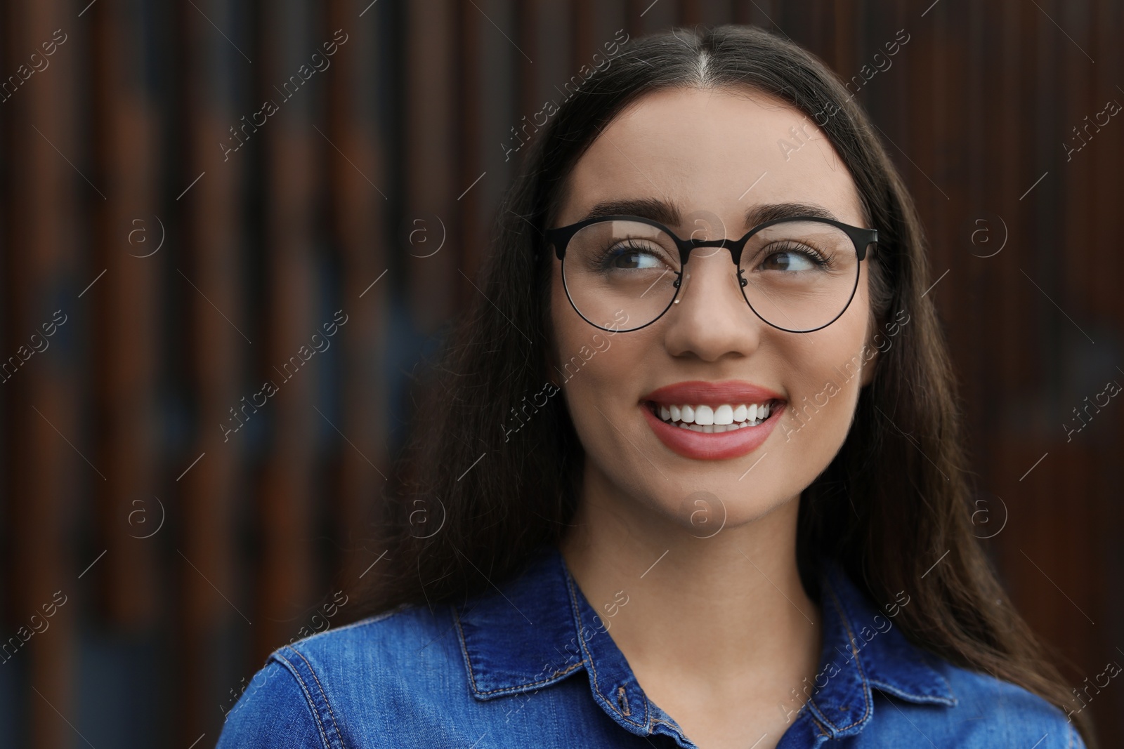 Photo of Portrait of beautiful woman in glasses on blurred background. Attractive lady smiling and posing for camera. Space for text