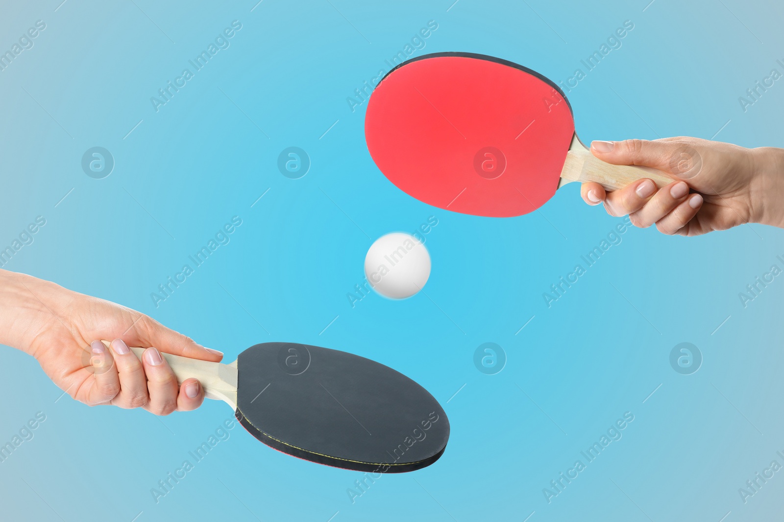 Image of Women with ping pong paddles and ball on light blue background, closeup