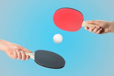 Women with ping pong paddles and ball on light blue background, closeup