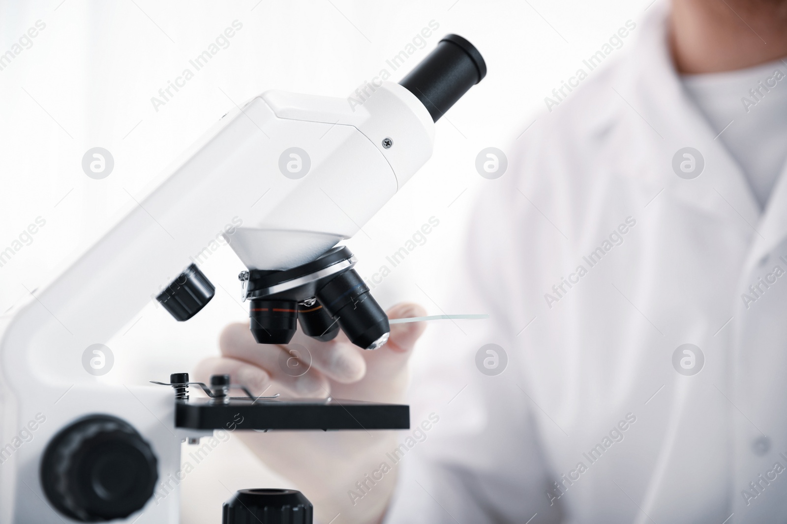 Photo of Scientist with test slide and microscope in laboratory, closeup. Medical research
