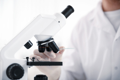 Photo of Scientist with test slide and microscope in laboratory, closeup. Medical research