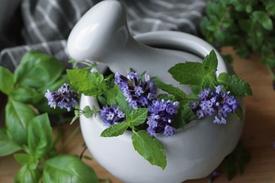 Photo of Mortar with fresh lavender flowers, mint and pestle on table, closeup