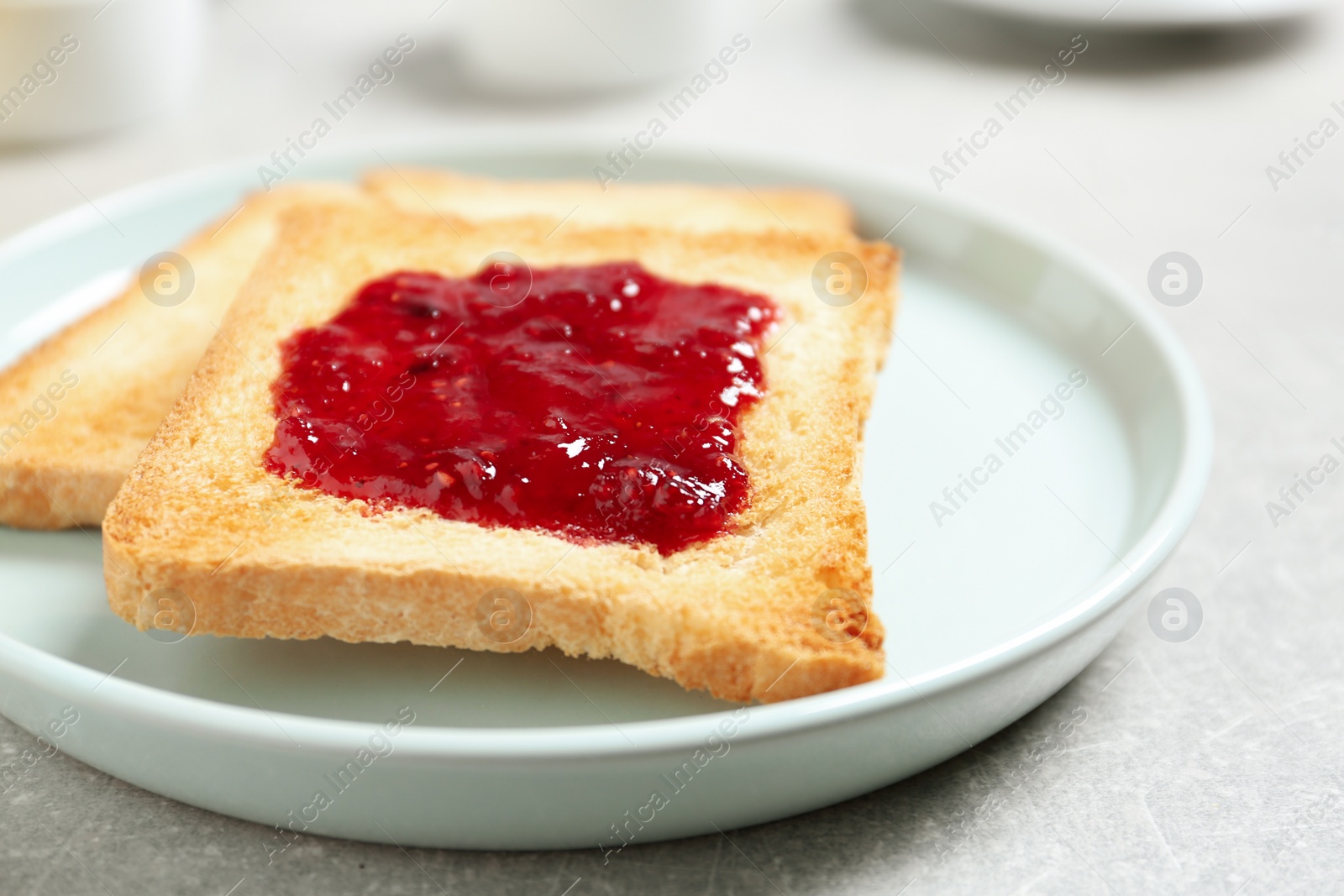 Photo of Fresh toasts with jam for breakfast on light grey table, closeup