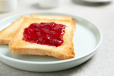 Fresh toasts with jam for breakfast on light grey table, closeup