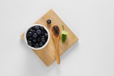 Ripe bilberries and leaves on white table, top view