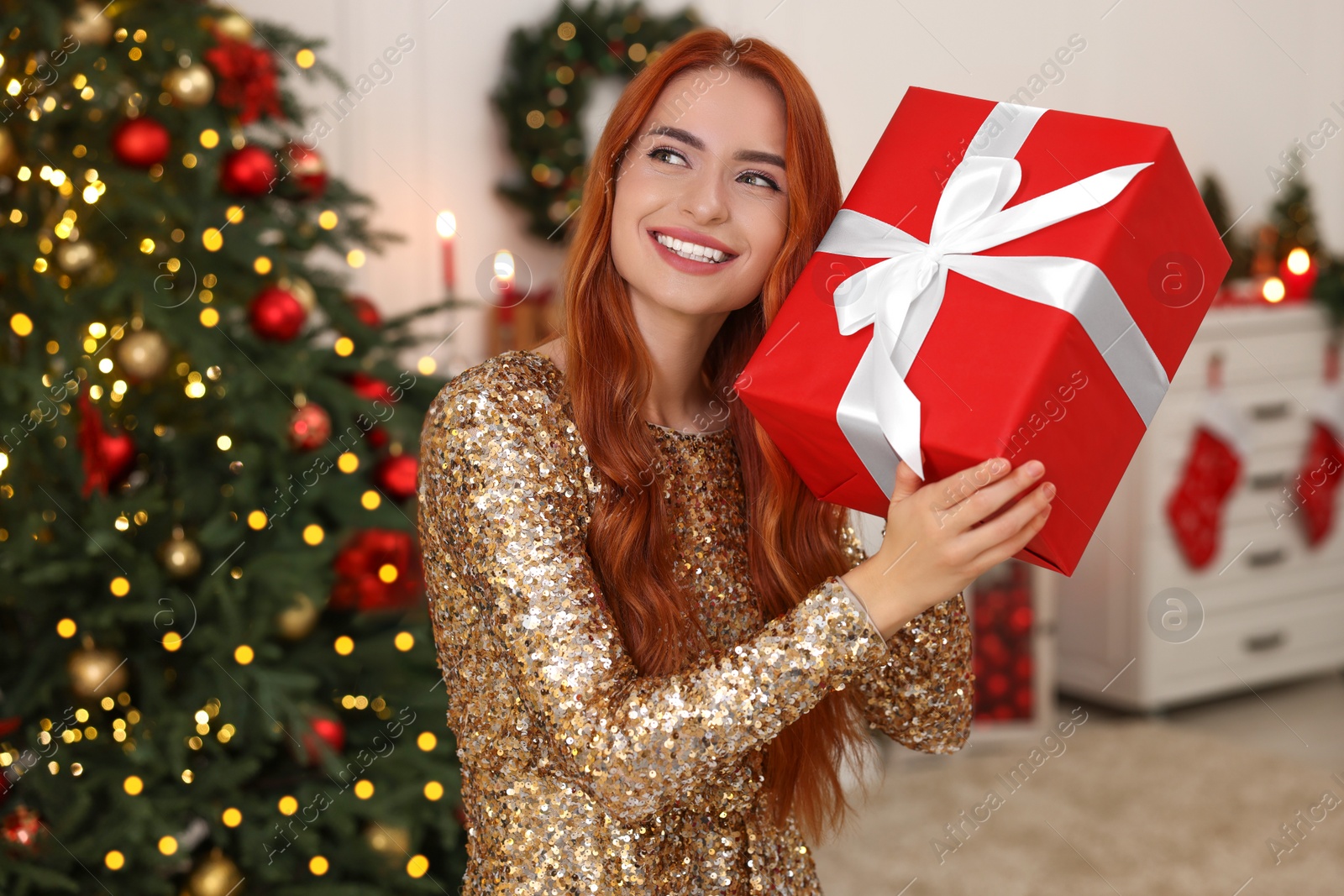 Photo of Happy young woman with Christmas gift at home