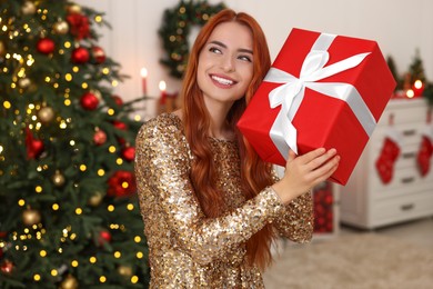 Happy young woman with Christmas gift at home