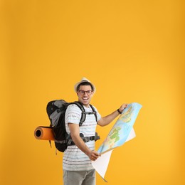 Photo of Excited male tourist with travel backpack and map on yellow background