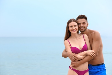 Photo of Young woman in bikini with her boyfriend on beach, space for text. Lovely couple