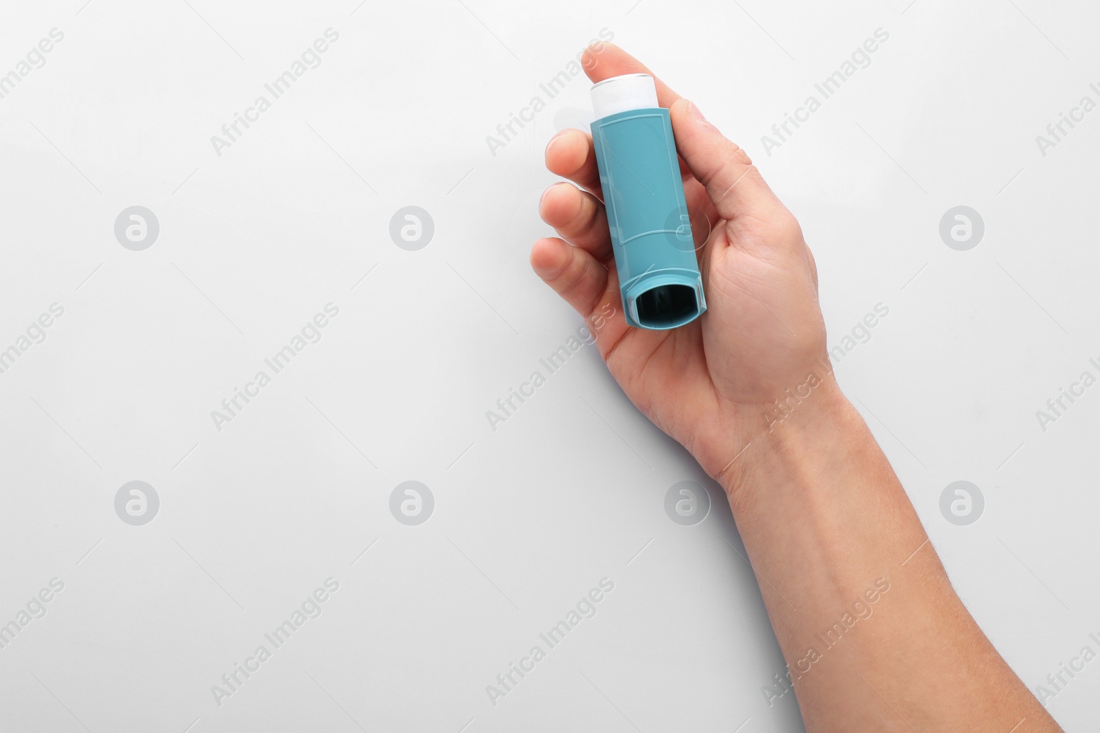 Photo of Man holding asthma inhaler on white background, top view