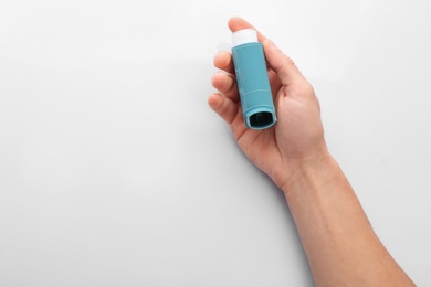 Man holding asthma inhaler on white background, top view