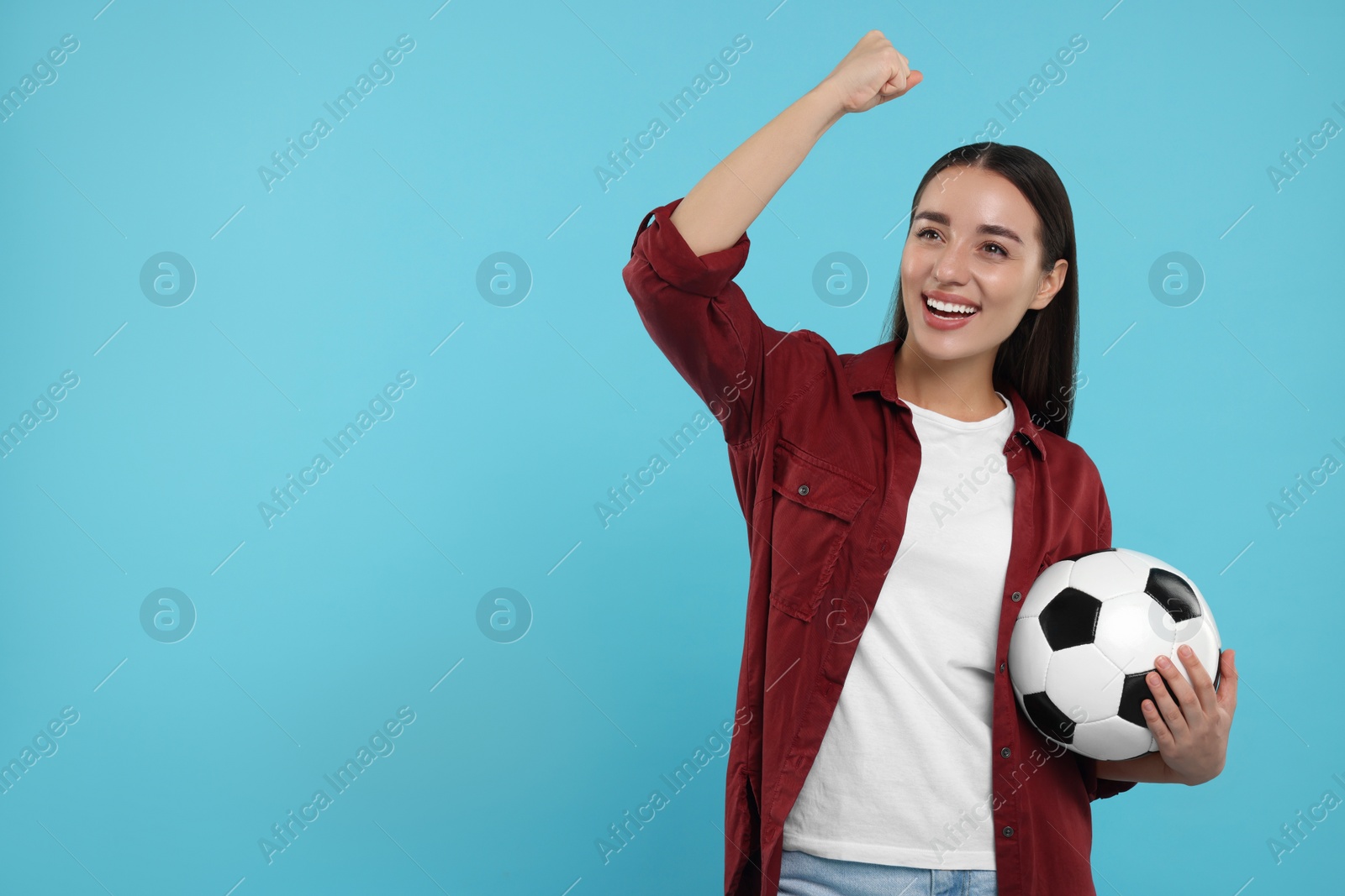 Photo of Happy fan holding soccer ball and celebrating on light blue background, space for text